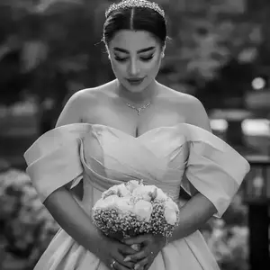 عکس عروس در حالی که سرش پایین است و به دسته گل عروسی نگاه می کند